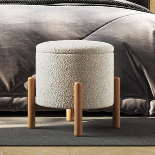Light gray boucle ottoman with wooden legs being used as side table with decorative items on top