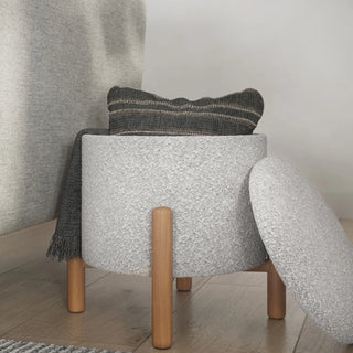 Round boucle storage ottoman positioned in living room setting next to sofa showing versatile use