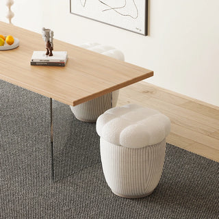 Boucle ottoman tucked neatly under a desk, used as a space-saving footrest or stool.