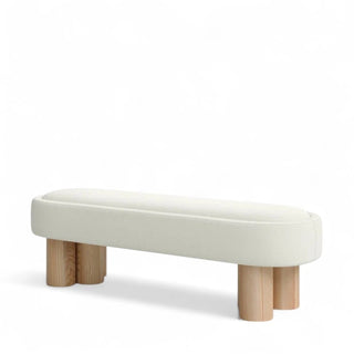 Side angle view of a minimalist cream boucle bench with a softly curved rectangular seat and four cylindrical light wood legs, set against a white background.