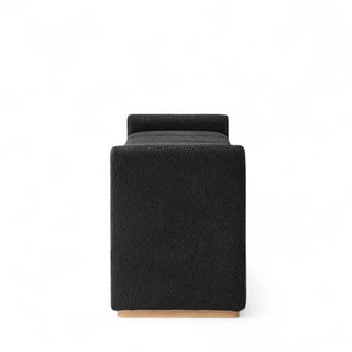 Side profile of black boucle ottoman showing piano key design detail and wooden leg construction
