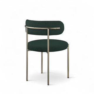 Three-quarter angle view of forest green boucle dining chair showing curved back design and metal frame construction