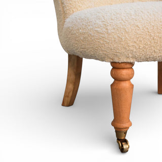 Close-up of a chair with wooden legs and a beige cushioned seat on a white background