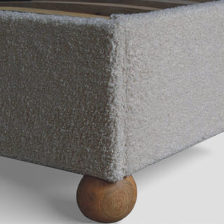 Gray upholstered bed with wooden footboard on a white background