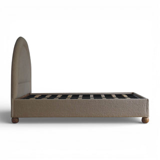Beige upholstered bed frame with wooden legs on a white background