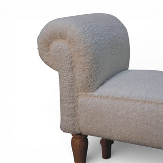 Corner of a textured armchair with wooden legs on a white background
