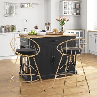 Pair of boucle counter stools with black seats and gold frames positioned at dark kitchen island