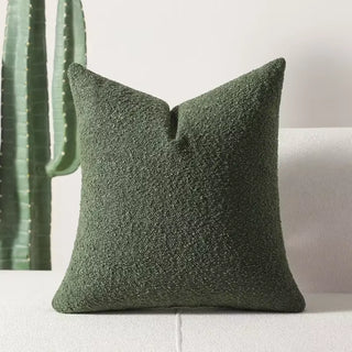 Olive green boucle pillow cover with thick texture set against a white sofa backdrop.