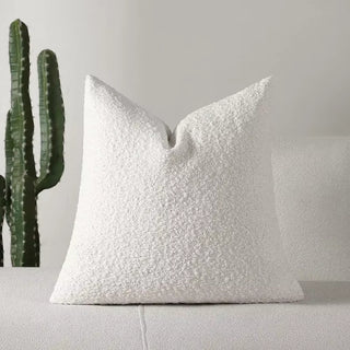 Clean white boucle pillow cover styled in soft daylight with gentle folds and cozy appeal.
