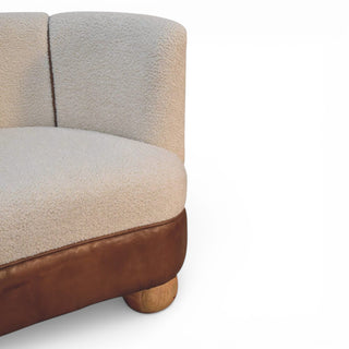 Section of a sofa with beige fabric and brown leather trim on a white background