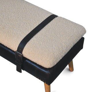 Small ottoman with a textured beige cover and black strap on a white background