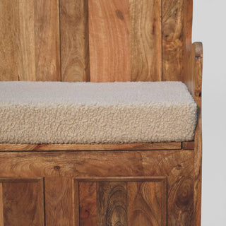 Wooden bench with a textured beige cushion against a wooden panel background