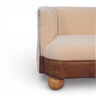 Beige sofa with brown leather trim and wooden legs on a white background