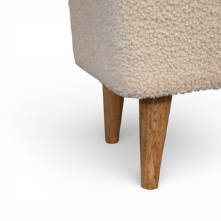 Close-up of a textured beige upholstered chair with wooden legs on a white background
