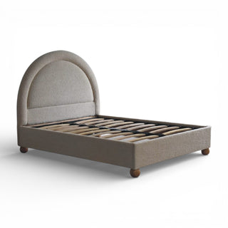 Beige upholstered bed with wooden legs on a white background