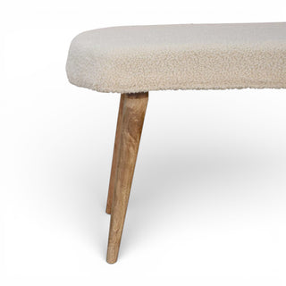 Beige cushioned bench with wooden legs on a white background