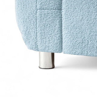 Detail of stainless steel leg on light blue boucle armchair showing modern base design