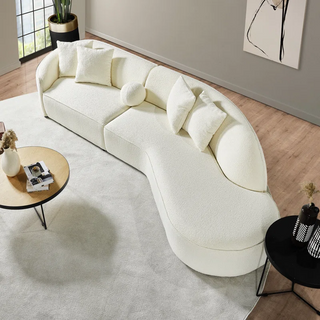 Curved white sectional positioned in bright contemporary living room with large windows and minimal decor
