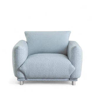 Light blue boucle armchair with thick cushion and modern stainless steel legs shown from front