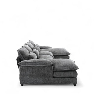 Side profile of gray boucle sectional sofa showing plush oversized cushions, deep seating, and textured fabric upholstery with dark legs