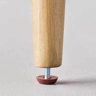 Detail shot of rubberwood ottoman leg with protective floor pad