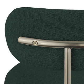 Detail of gold metal frame meeting green boucle upholstery on chair