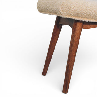 Close-up of a chair with wooden legs and beige cushioned seat on a white background