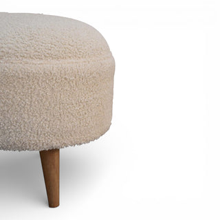 Round ottoman with beige textured top and wooden legs on a white background