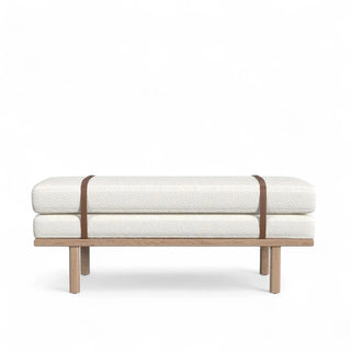 Cream boucle upholstered bench with natural wood frame and caramel leather straps shown from front angle