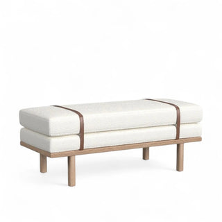 Cream boucle upholstered bench with natural wood frame and caramel leather straps shown from quarter angle