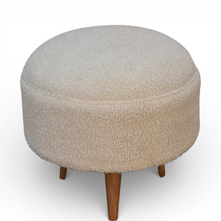Round ottoman with sheepskin texture and wooden legs on a white background
