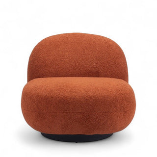 Terracotta boucle lounge chair with smooth curved silhouette and circular black base photographed against white background