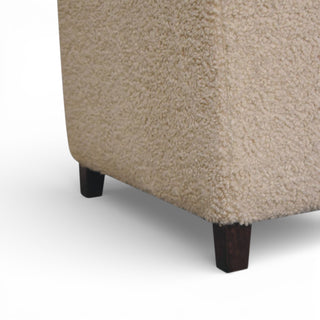 Close-up of a textured beige upholstered corner piece with dark wooden legs on a white background