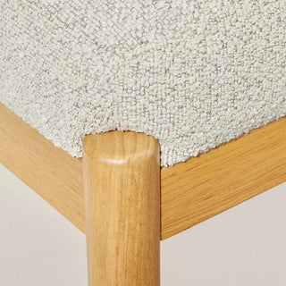 Close-up detail of white boucle upholstery texture and wooden frame corner