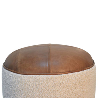 Round ottoman with brown leather top and textured beige base on a white background