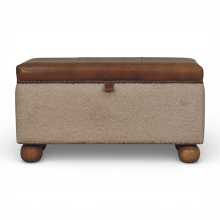 Beige storage ottoman with brown leather top and legs on a white background