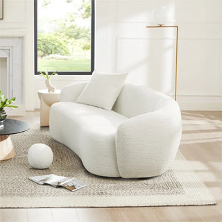 Side angle view of the white boucle sofa styled in a softly lit room with a neutral palette and modern accents.