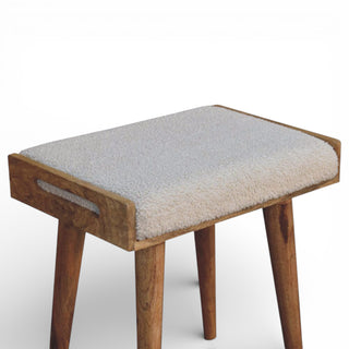 Wooden stool with a textured cushion on a white background