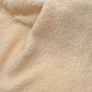 Close-up of beige teddy fabric highlighting its plush texture and natural folds.