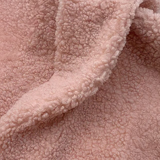 Close-up of blush teddy fabric showing soft, textured surface with gentle waves.