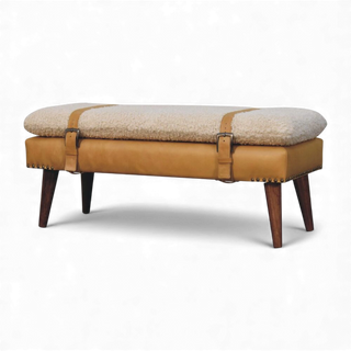 Three-quarter angled view of the Bouclé Bench Cream Tan Leather X-Strap from the left side showing the cushioned top, leather X-straps, and wooden legs.

