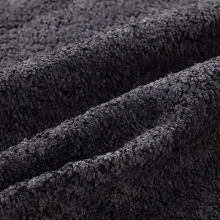 Close-up of charcoal bouclé fabric showing diagonal folds and nubby texture.