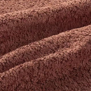 Close-up of chocolate brown bouclé fabric with diagonal folds, showcasing its textured, looped surface pattern