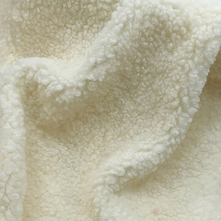 Close-up of cream teddy fabric featuring cozy, plush surface with subtle draping.