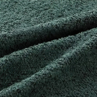 Close-up of forest green bouclé fabric with three diagonal folds, showing its rich textured, looped surface.