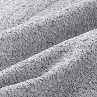 Close-up of light grey bouclé fabric showing three diagonal folds with distinctive looped texture.