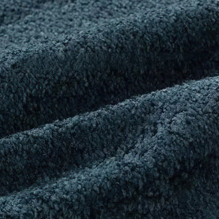 Close-up of petrol blue bouclé fabric with diagonal pleats, showcasing its rich textured surface.