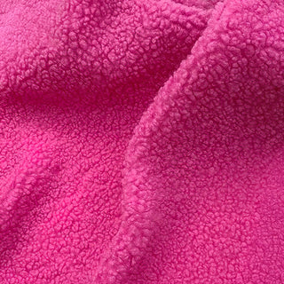 Close-up of fuchsia pink teddy fabric displaying rich, soft texture with natural folds.