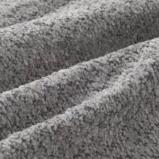 Close-up of silver grey bouclé fabric featuring diagonal folds and characteristic looped texture.