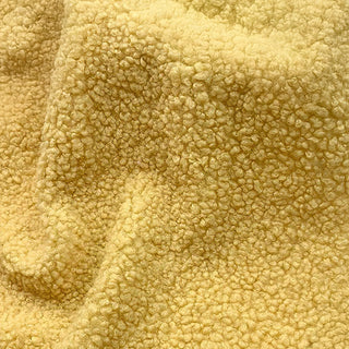 Close-up of yellow teddy fabric showing rich, soft texture with natural folds.